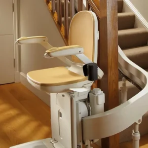 A reconditioned Acorn or Brooks 180 T565 Curved Stairlift with armrests is installed along a carpeted staircase with a wooden bannister in a home.